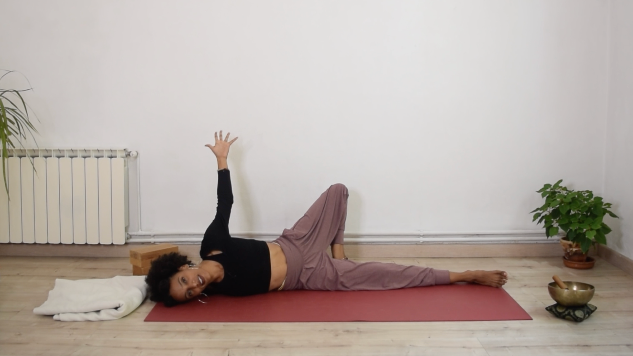 Yoga instructor Laia Bové practicing Broken Wing pose, lying on her side with one arm extended.